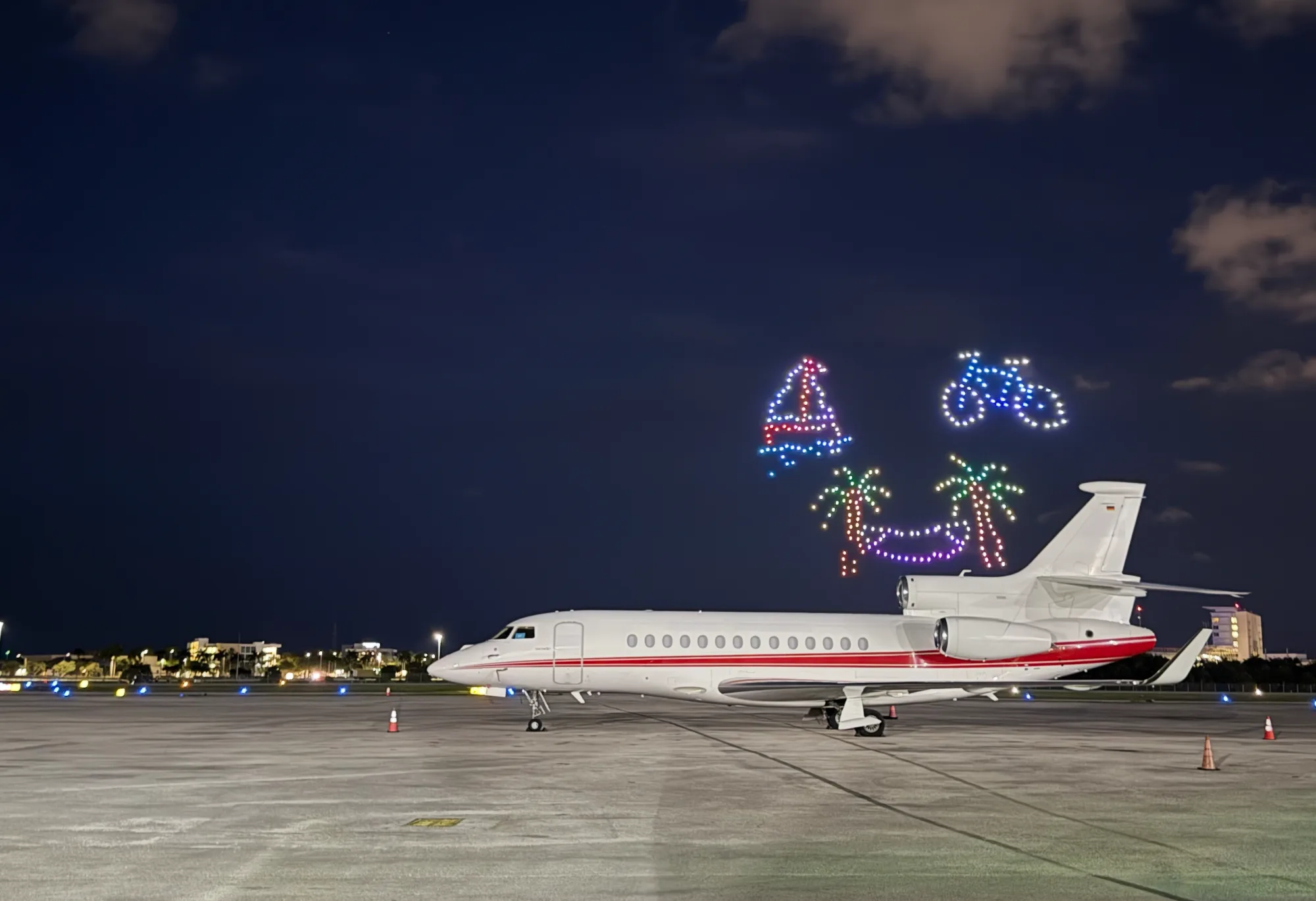 Jet on the Boca Raton Airport ramp at night beneath a drone light show
